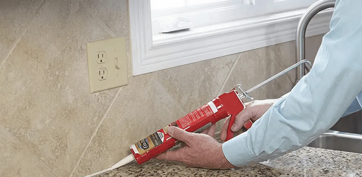 Handyman applying caulk along a kitchen backsplash and countertop seam in Hollywood, FL